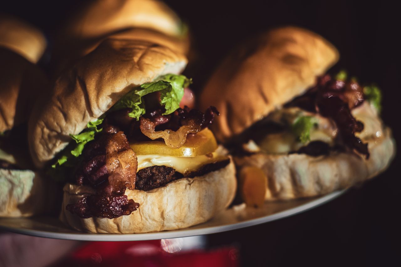 Burgers maison au bacon grillé, cheddar fondu et salade, présentés sur un plateau