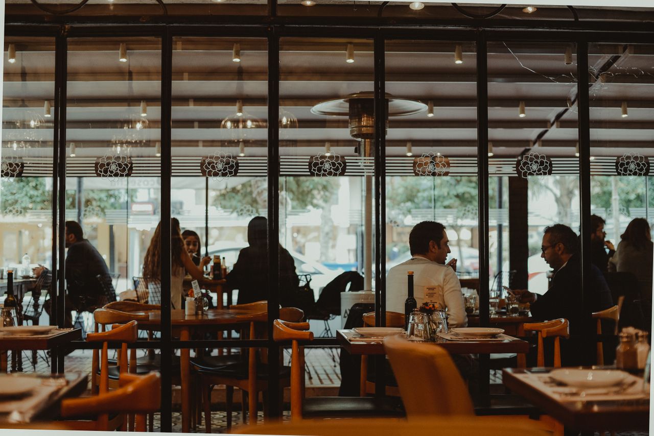 Salle de restaurant lumineuse vue depuis la baie vitrée, tables en bois dressées